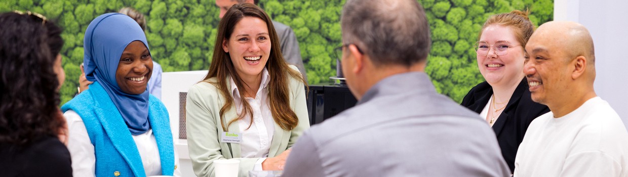 Gesprächssituation am Messestand: Sechs Personen lachen sich an.