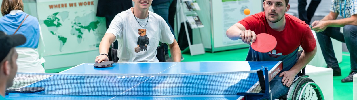 Rollstuhlfahrer spielen Tischtennis.