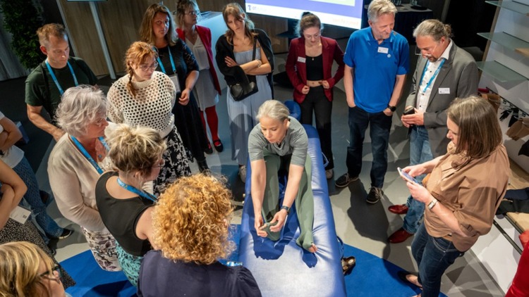 Eine Frau im Zentrum des Bildes präsentiert zahlreichen Interessenten spezielle Strümpfe.