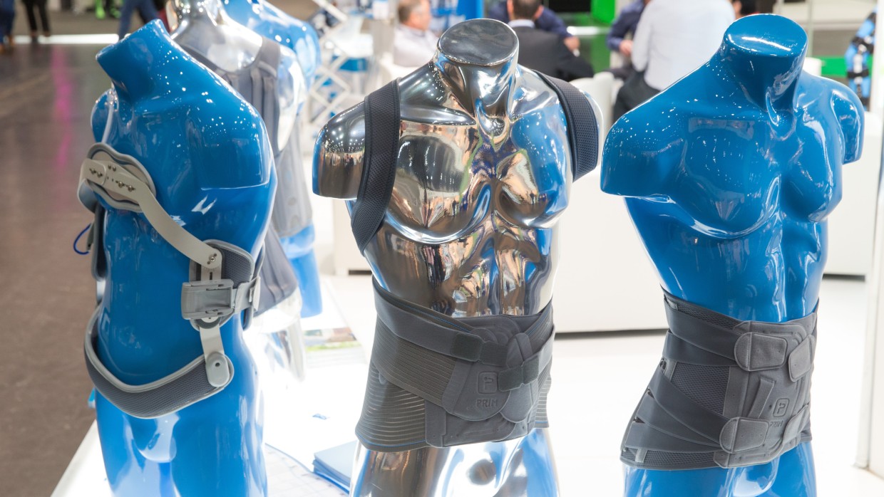 Three blue torso mannequins wearing orthopedic back and torso braces at a trade fair booth. Three blue torso mannequins wearing orthopedic back and torso braces at a trade fair booth.