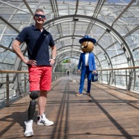 A man with a prosthetic leg on the right poses in the tube to the glass hall. In the background is the little fair man. A man with a prosthetic leg on the right poses in the tube to the glass hall. In the background is the little fair man.