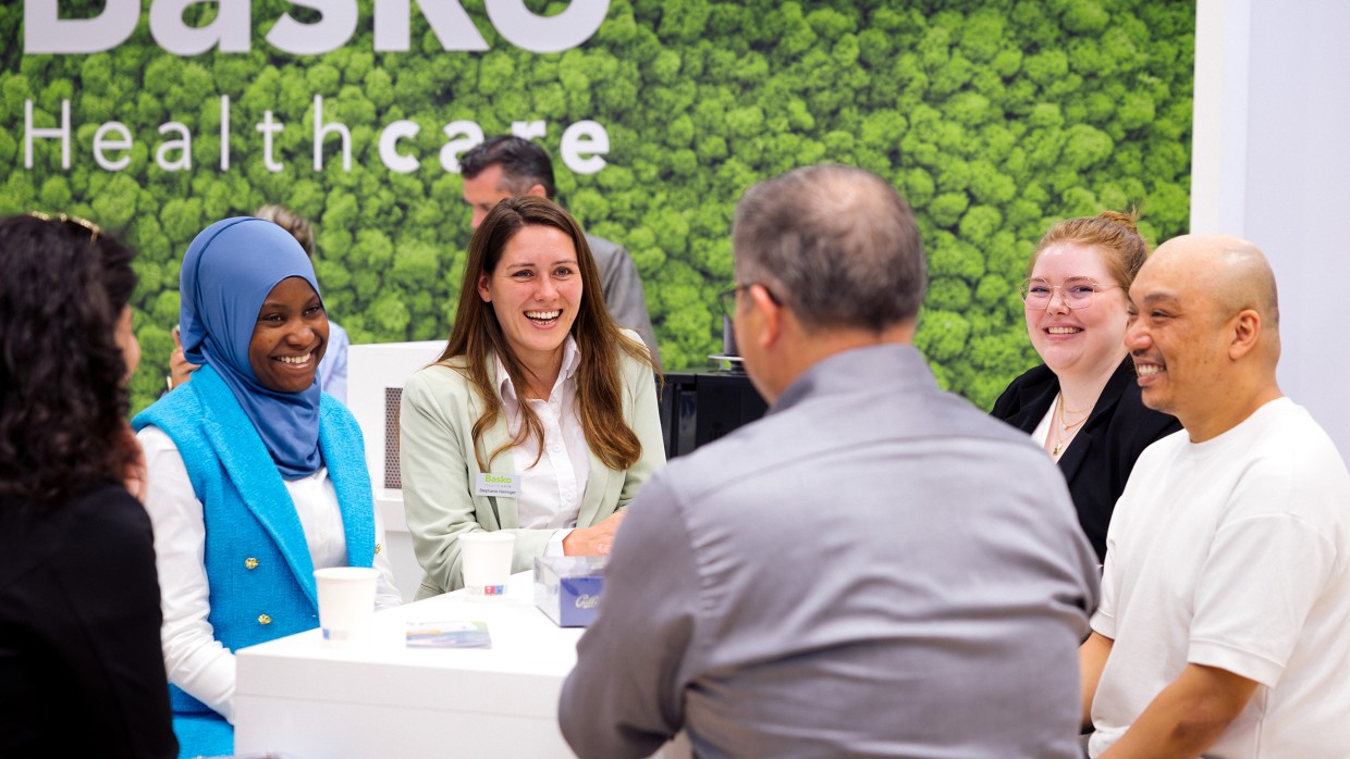 Conversation situation at the trade fair stand: six people laughing at each other.