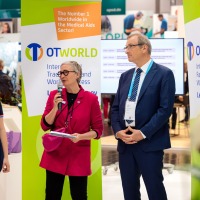 Four people at an official speech at OTWorld, a woman with a microphone speaks, next to her two men in suits and a young woman with a prosthesis. Four people at an official speech at OTWorld, a woman with a microphone speaks, next to her two men in suits and a young woman with a prosthesis.