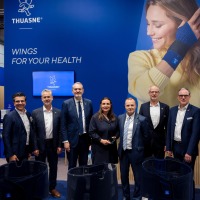 Group photo of trade fair visitors at the Thuasne booth at OTWorld, in front of a blue wall with the slogan ‘Wings for your health’ and a large image of a woman wearing a wrist brace. Group photo of trade fair visitors at the Thuasne booth at OTWorld, in front of a blue wall with the slogan ‘Wings for your health’ and a large image of a woman wearing a wrist brace.