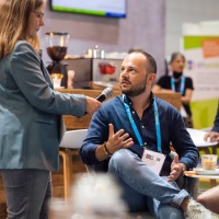 A man, sitting on a chair, is being interviewed by a woman. A man, sitting on a chair, is being interviewed by a woman.