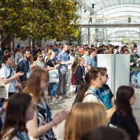 Large crowd in the glass hall, many young visitors wearing trade fair passes and moving around the room. Large crowd in the glass hall, many young visitors wearing trade fair passes and moving around the room.