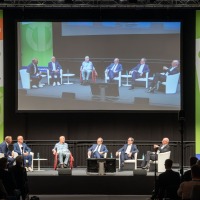 Panel discussion at OTWorld with seven experts on stage, their conversation displayed on a large screen, surrounded by OTWorld banners. Panel discussion at OTWorld with seven experts on stage, their conversation displayed on a large screen, surrounded by OTWorld banners.