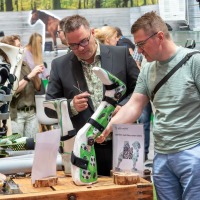 Two men examining child-friendly orthoses with soccer motifs at an exhibition booth with a green backdrop at OTWorld. Two men examining child-friendly orthoses with soccer motifs at an exhibition booth with a green backdrop at OTWorld.