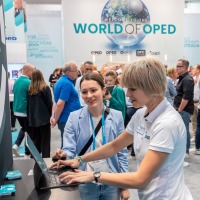 Two women looking at a laptop together. In the background, trade fair activities. Two women looking at a laptop together. In the background, trade fair activities.