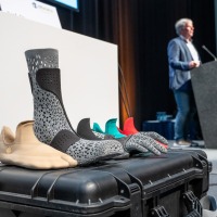 Innovative orthopedic foot and lower leg orthoses in various designs on a transport case, with a presentation taking place in the background at OTWorld Innovative orthopedic foot and lower leg orthoses in various designs on a transport case, with a presentation taking place in the background at OTWorld