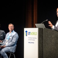 Expert presentation at OTWorld in Leipzig – a speaker presents at the podium while two other professionals listen attentively. Expert presentation at OTWorld in Leipzig – a speaker presents at the podium while two other professionals listen attentively.