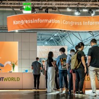 Visitors stand at the OTWorld congress information desk to obtain information. Visitors stand at the OTWorld congress information desk to obtain information.